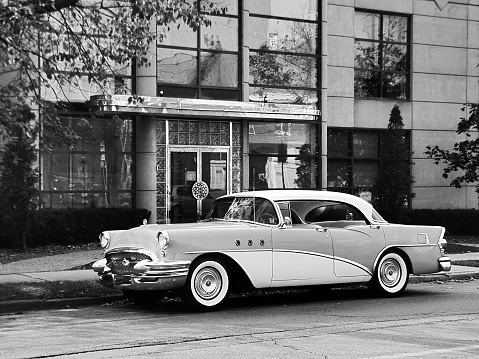 1950's sedan parked outside an office building.