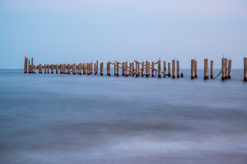 old wood pillars in the water  long exposure shoot in staten island beach, new york