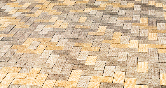 A large area of exterior flooring, made up from modern, grooved bricks arranged in a herringbone pattern.