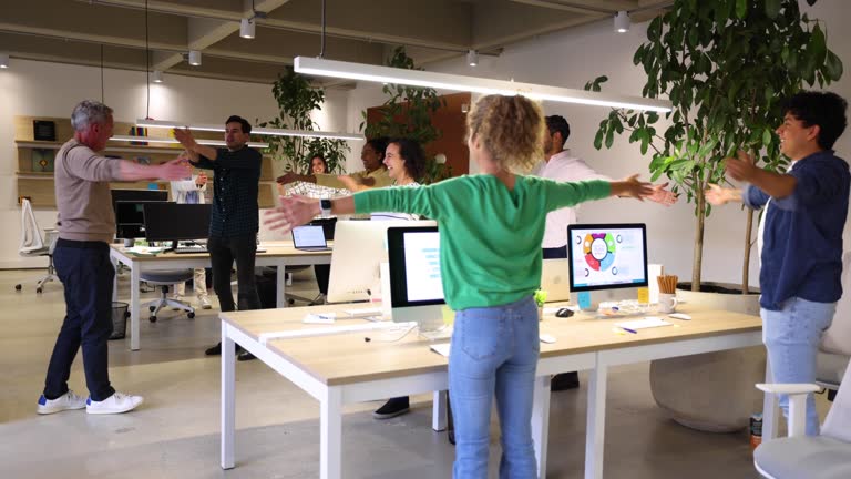 Diverse group in age and race following team leader while doing some exercises at the office of their occupational health program