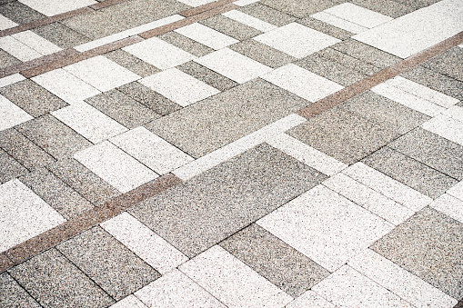 Modern design - stone tiles of different sizes and shades arranged together to make up a modern city paving surface.