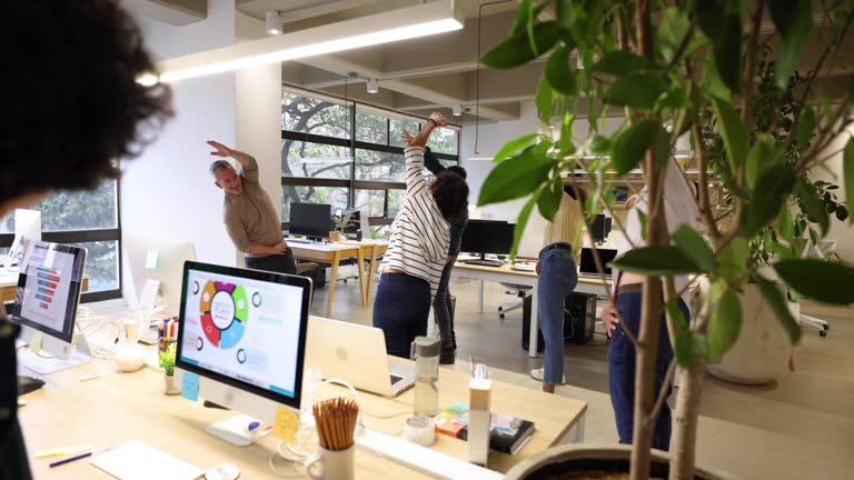 People at the office following the team leader doing some stretching exercises for their occupational health program