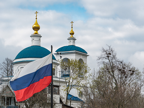 Russian flag on the background of church domes, trees and flying birds. High quality photo