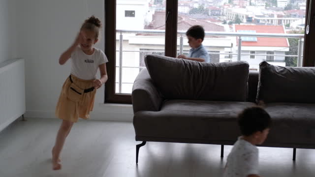 Cheery siblings play tag game together in modern living room