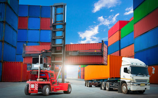 istock Container Crane Tractor Unloading Container Box with Trailer Truck. Handling of Logistics Transportation Industry. Cargo Container ships, Freight Trucks Import-Export. Distribution Warehouse Shipping. 1484871372