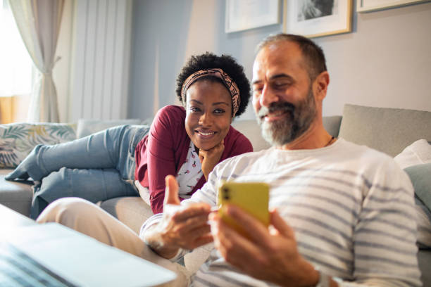 istock Young couple using a phone on the couch at home 1484873819