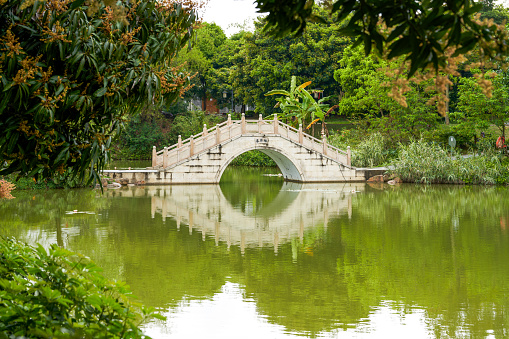 Stone arch bridge over lake in Chinese park