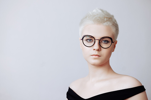 Portrait of beautiful blonde woman with short haircut in black glasses isolated on white background.