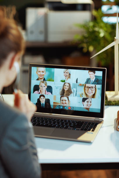 Seen from behind modern woman with laptop having webcam meeting stock photo