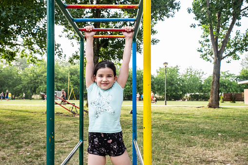 a beautiful little girl climbs on the playground and laughs