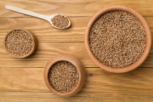 Bowls with wholegrain spelt farro on wooden background. Top view.