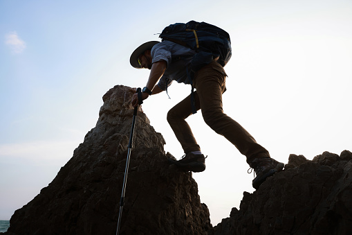 Male hiker climbing up mountain cliff , adventure travel on cliff mountain, backpacker adventure travel lifestyle