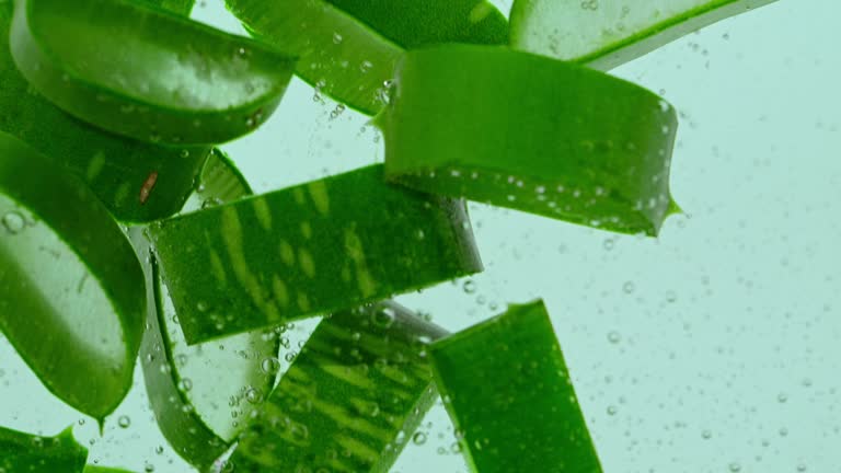 Aloe vera slices falling into water.