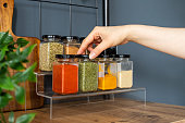 Cropped hand holding jar of spices on kitchen.