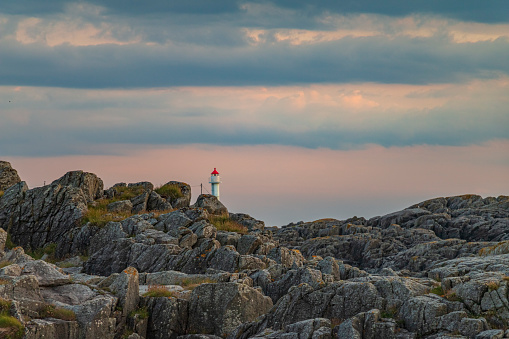 Lighthouse on rocky Norwegian coast with sunset colours