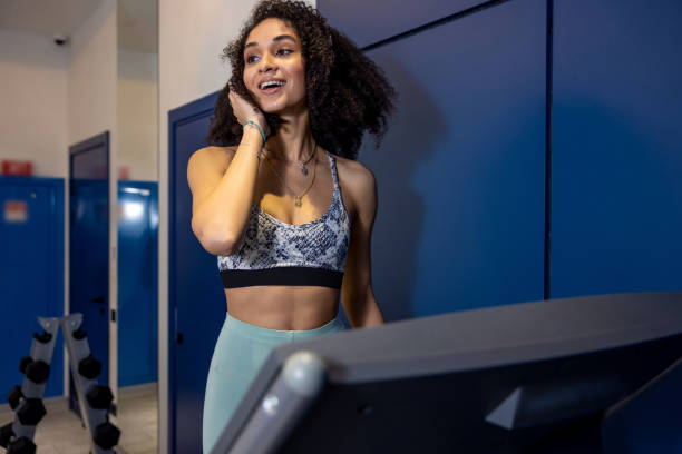 istock Curly-haired young woman on a treadmill looking contented 1484893623