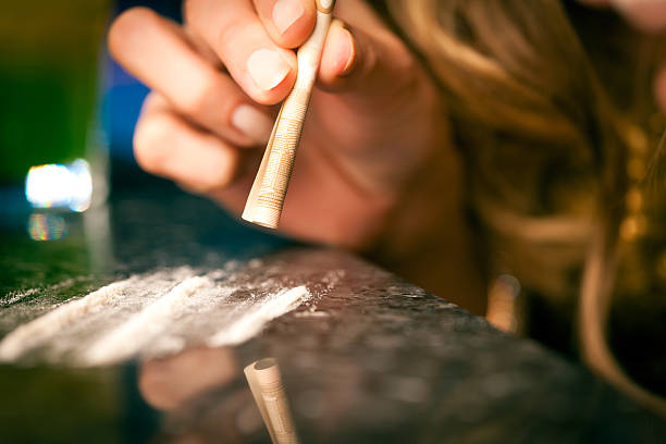 Young woman snorting cocaine with rolled up dollar Young woman snorting cocaine with a bill, close-up cocaine photos stock pictures, royalty-free photos & images