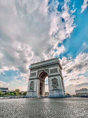 Long Exposure Shows an Empty Pl. Charles de Gaulle traffic circle at the Arc de Triomphe in Paris, France at Sunset with Vibrant Sky and Cumulus Clouds in the Summer