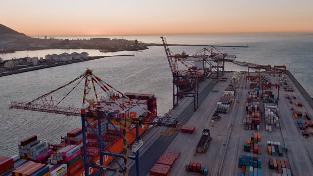Aerial.Cranes removing containers from a Container ship in a harbour at sunset.Global supply chain.Logistics.Distribution