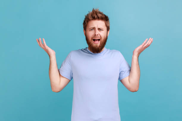 istock Man in blue T-shirt standing with raised hands and indignant face asking why, annoyed by problem. 1484904867