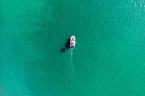 Aerial drone photo of rib speed boat cruising in tropical exotic bay with emerald sea.