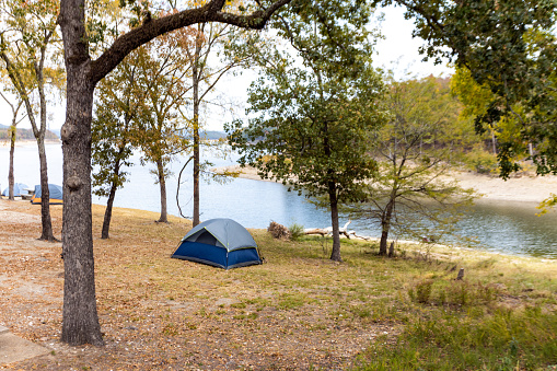 Camping tents near a beautiful lake among trees, campsite, adventure vacation concept, Broken bow lake in Oklahoma, USA.