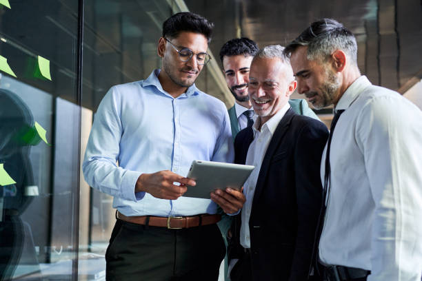 Young man using a digital tablet showing his project to his boss and colleagues at workplace.
