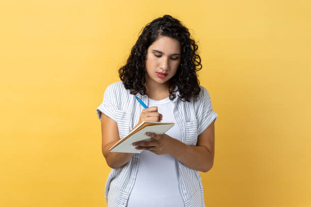 istock Serious woman writing in paper notebook, making to do list, writing her schedule. 1484905635