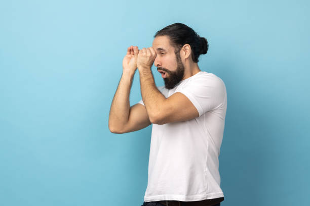 istock Man looking through monocular gesture and expressing surprise, zooming vision, exploring distance. 1484906022