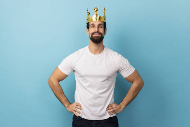 istock Man in gold crown, standing with hands on hips, looking at camera with conceited expression. 1484906033