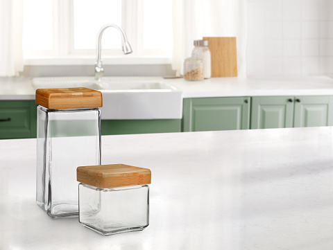 Empty glass containers in a kitchen with a marble counter top and sink in the background
