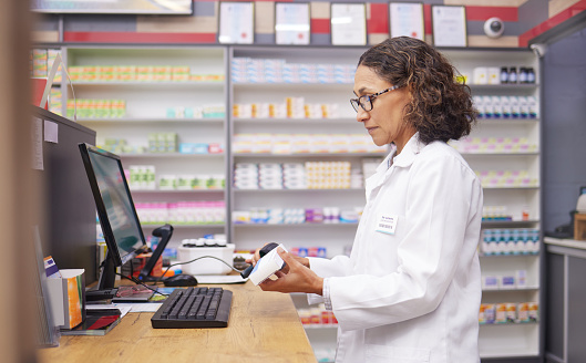 Order, pills and pharmacist scanning medicine at a checkout for service at a pharmacy. Healthcare, medical and woman on a hospital pc to scan a box for a prescription, inventory and medication check