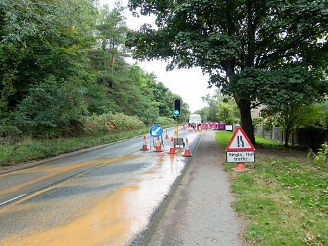 Roadworks traffic lights cones and water leaks, a country road in rural England with workmen trying to fix one of many water leaks that waste vast amounts of water.