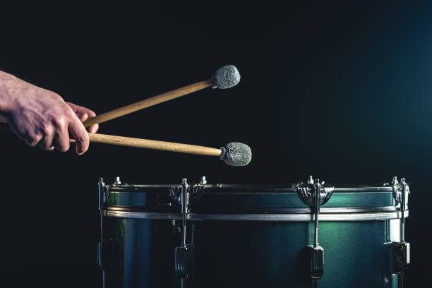 мужчина играет на музыкальном ударном инструменте с палочками на темном фоне. - samba dancing dancing drum drumstick стоковые фото и изо�бражения