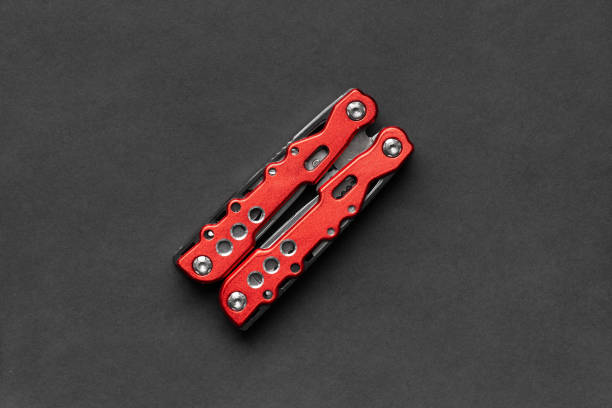 Folded universal multifunctional pliers with different nozzles on a black background. Versatile camping knife. Multifunctional tool.
