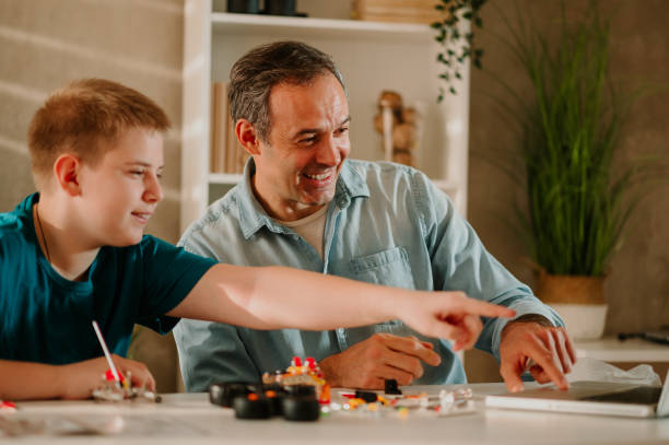 istock Young boy is pointing his finger to the laptop screen while father is laughing. 1484922173