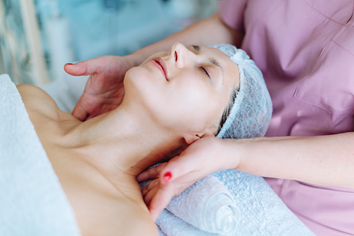 Cosmetologist making face massage at beauty salon