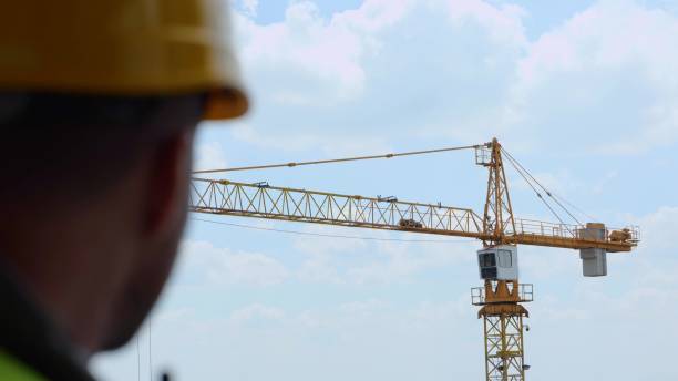 istock Big construction crane working at construction site outdoor on blue sky background. Huge professional industrial tower crane works at building site in city. Building industry 1484929788
