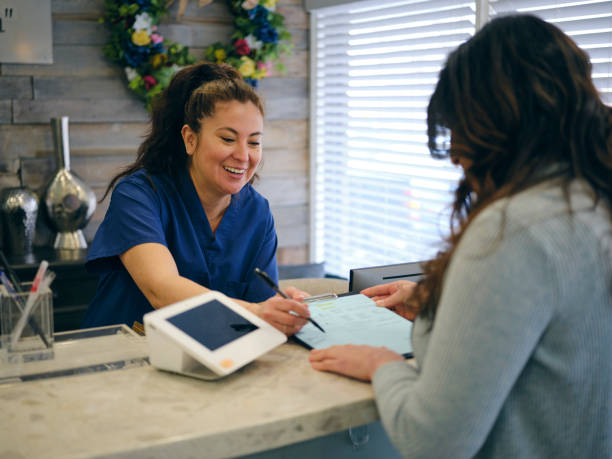 recepción en un consultorio médico - healthcare and medicine receptionist paying credit card fotografías e imágenes de stock