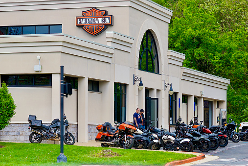 Fairfax, Virginia, USA - April 23, 2023: Two men look at motorcycles for sale outside a Harley-Davidson Motorcycles store.