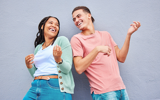 Dance, funny and interracial couple with air guitar on a wall for bonding, fun and playful in the city. Smile, laughing and black woman with a man playing an imaginary instrument for comedy together