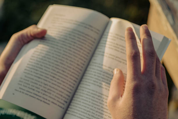 young man reading a book outdoors