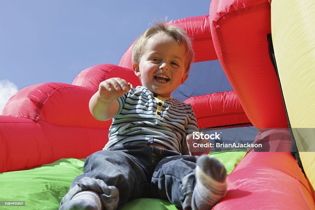 Niño en tobogán inflable castillo inflable para saltar - Foto de stock de Castillo inflable para saltar libre de derechos