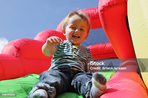 Niño En Tobogán Inflable Castillo Inflable Para Saltar Foto de stock y más banco de imágenes de Castillo inflable para saltar