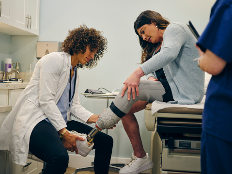 A doctor with her amputee patient, adjusting the patient’s prosthetic limb.