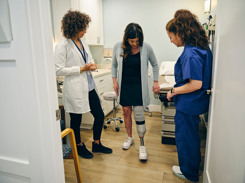 A doctor with her amputee patient, adjusting the patient’s prosthetic limb.