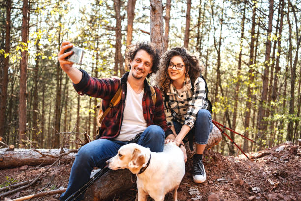 istock Young adventurous couple taking selfies with their white dog while on a hike 1484934917