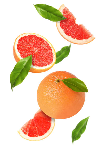 istock Tasty ripe grapefruits and green leaves falling on white background 1484936396