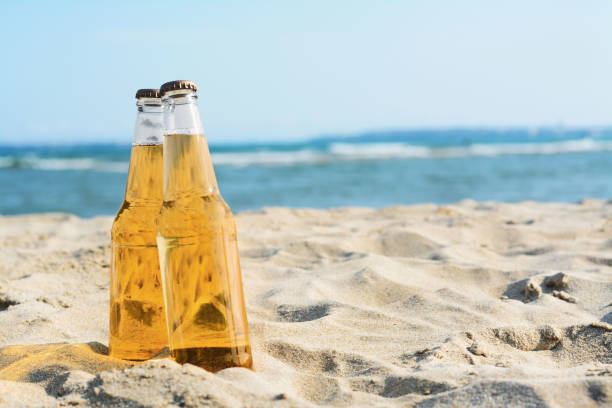 istock Bottles of cold beer on sandy beach near sea, space for text 1484937982