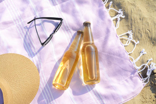 istock Bottles of beer and beach accessories on sand, flat lay 1484938000